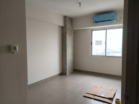 Sebelum — ruang tamu unit serah terima dengan keramik developer dan kardus serah terima di lantai