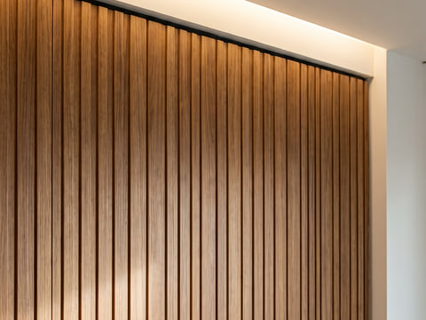 Detail wall panel HPL kayu dengan alur vertikal, pertemuan panel dengan plafon gypsum dan cove lighting