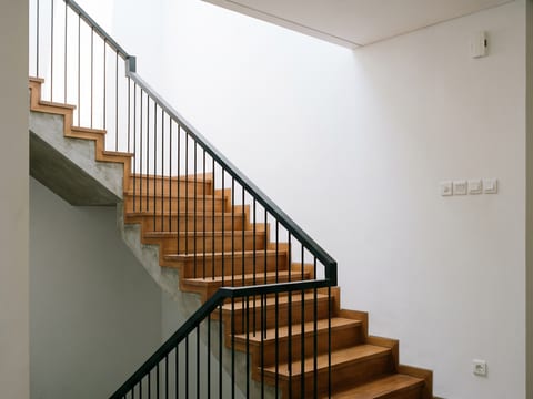 Tangga dengan pelapis kayu solid dan railing besi hollow finishing powder coating hitam