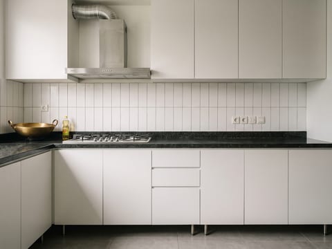 Zona basah dapur dengan top granit dan backsplash keramik penuh sampai kabinet atas serta hood ducting keluar