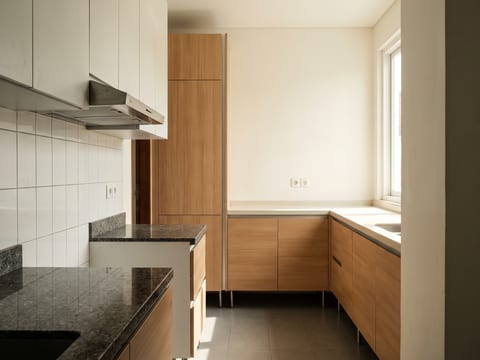 Dapur dilihat dari pintu masuk, pemisahan zona basah bertop granit dan zona kering bertop solid surface