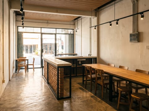 Kedai kopi dilihat dari pintu masuk, lantai semen ekspos bercoating dan track light terarah ke meja