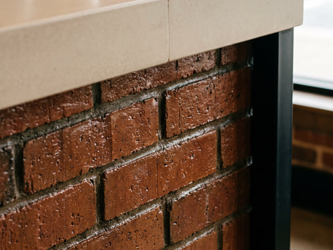 Detail pertemuan top solid surface bar dengan panel depan bata ekspos berfinishing coating bening