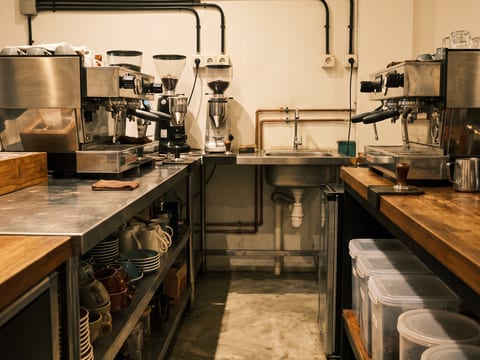 Jalur kerja di belakang bar selebar 90 cm dengan dua mesin espresso dan dua grinder di atas top solid surface