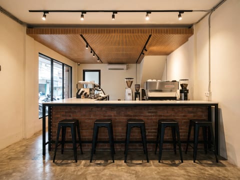 Bar kedai kopi di tengah bentang ruko dengan rangka besi hollow, top solid surface, dan panel bata ekspos