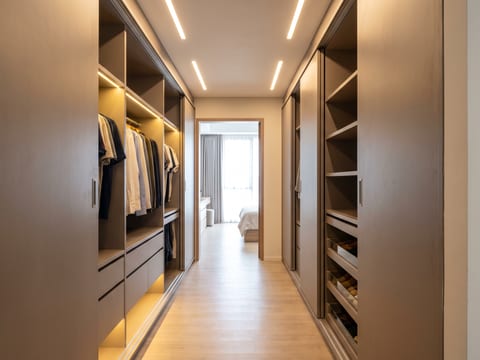 Lorong walk-in closet selebar 1,4 m dengan lemari dua sisi asimetris berfinishing HPL warm grey