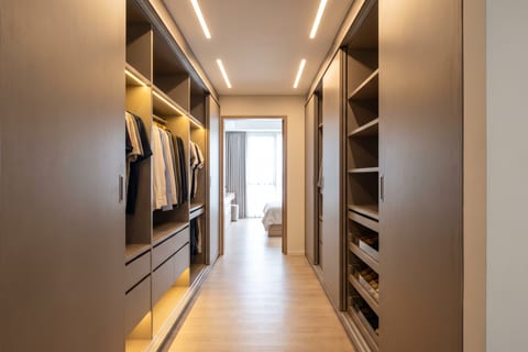 Lorong walk-in closet selebar 1,4 m dengan lemari dua sisi asimetris berfinishing HPL warm grey