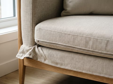 Sofa rangka kayu dengan sarung yang bisa dilepas dan dicuci pada unit studio untuk disewakan