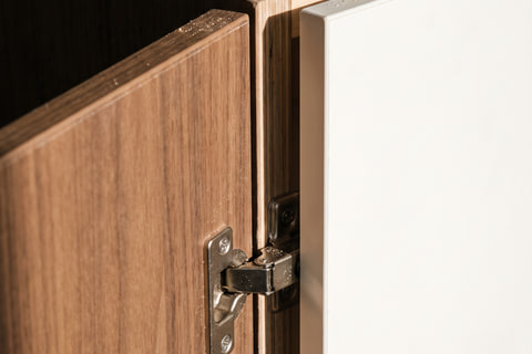 Detail pintu kabinet HPL walnut dengan edging PVC 2 mm dan engsel soft-close komponen standar pasaran