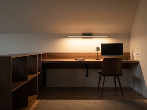 Zona meja kerja di dalam ruang keluarga dengan pencahayaan terpisah dan kaki furnitur ramping